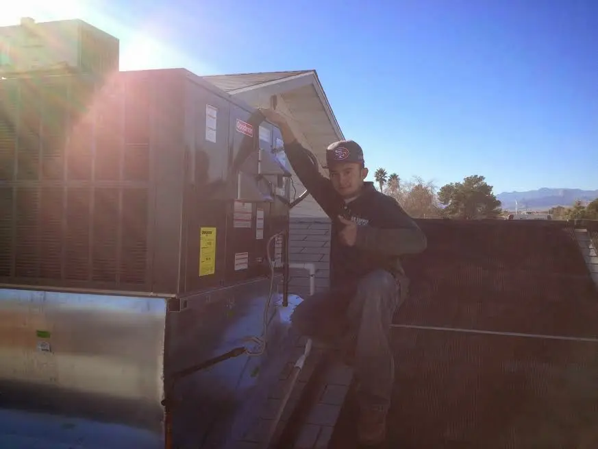 HVAC technician performing Boiler Repair on a rooftop unit in Grain Valley