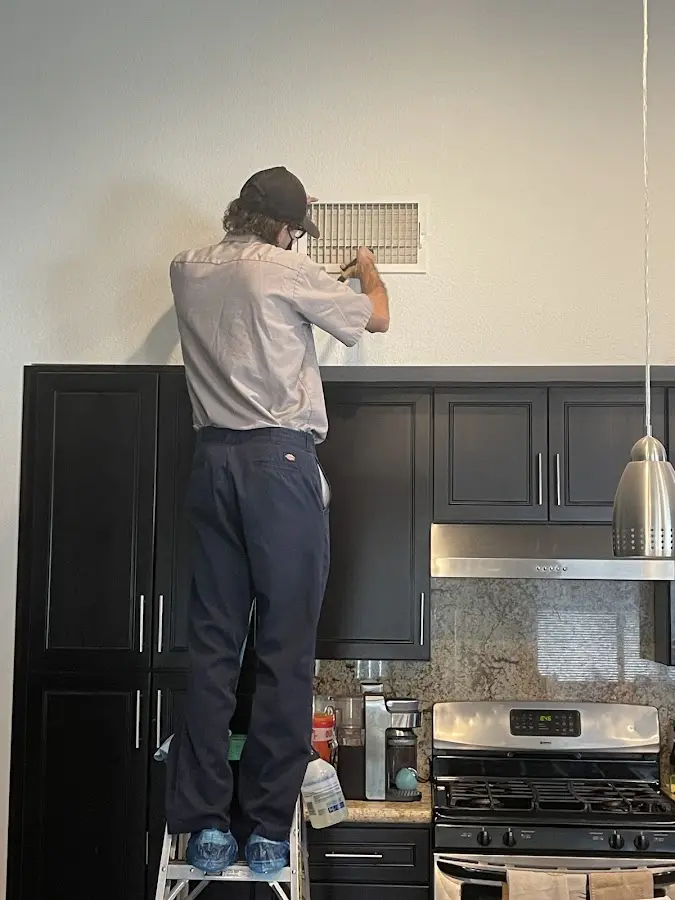 Technician inspecting an air vent during HVAC service in Grain Valley